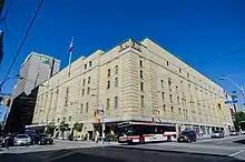 Panorama of the arena exterior with beige-coloured bricks and street scene at a downtown intersection