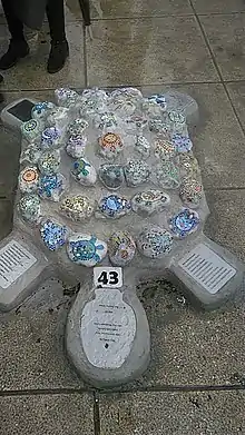 A concrete turtle whose shell contains 43 colorful turtles