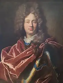 Head and upper body of a middle-aged man. His face is rounded with very white skin, his blue eyes are looking directly at the viewer. His hair is powdered grey and curled, and he's wearing armour covered by a red velvet cape.