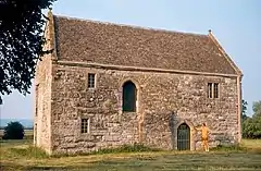 Yellow stone building with tiled roof and arched doorway.