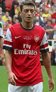 Mesut Özil is classified as having a migrant background because both of his parents were born in Turkey.