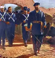 a formation of Marines wearing blue uniforms march through the gates of Mexico City, led by a drummer and officer with drawn sword