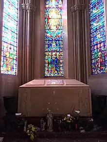 A large pink/cream-colored box in front of a stained glass window.