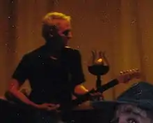 A man plays a guitar in a brown-tinted backdrop.