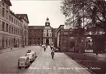 Black and white photograph of a street with buildings in front and to the left and a parterre to the right.