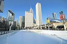 An empty ice skating rink with tall buildings in the background