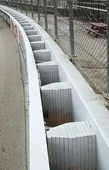 A white-colored SAFER barrier retrofitted in front of a concrete wall