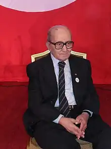 Mohamed Talbi seated, hands folded.