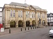 A large stone building with 12 glazed arched windows at first floor level above six stone arches