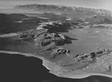 Chain of tall hills with sharp peaks. A crater and lake are in the foreground.