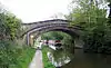 The bridge crosses the canal with a wide footpath on the left and long boats visible through the arch.