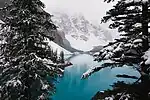 Lake and forest in front of high rocky mountains with snow.