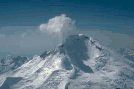 A snow-covered mountain, with a plume of steam and gas rising from the top