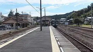 A view of the station platforms and tracks. There is a passing loop to the left between track 1 and the station building. To the right of track 2 is another passing loop and various sidings. Note the level crossing at the far end of the platform.