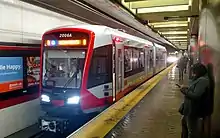 A red modern light rail vehicle at a subway platform