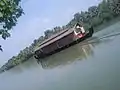 A houseboat moves through Ashtamudi Lake. Munroe island in the background.