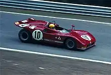 A man wearing a yellow helmet driving a red racecar