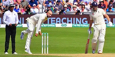 Lyon bowling while the non-striker and umpire watch