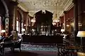 The classical style bar in the dining room, National Liberal Club, London (1884–87), an example of Waterhouse's furnishings, made of solid mahogany, note the geometrical patterns of the ribs in the plasterwork ceiling and the pendant light fittings