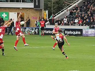 A rugby player pictured after kicking a ball, with one leg extended in the air and the other placed on the ground