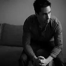 A white and black photo of a white man sitting down