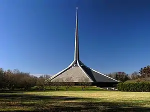 Hexagonal gray-roofed building with a spire about twice as tall as the building itself