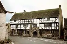 White-fronted building with black beams prominent. Over the door is a sign saying The George Inn, Wadworths.