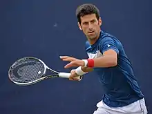 Tennis player Novak Djokovic preparing to hit a shot.