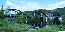 A bridge with three wooden arches, spanning a river