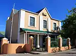 This stately double-storeyed house was erect by the immigrant Heinrich Wilhelm Becker in 1876.
He was Mayor of Ladismith for an unbroken period of 32 years.
Type of site: House
Current use: Residential.
This stately double-storeyed house was erect by the immigrant Heinrich Wilhelm Becker in 1876.
He was Mayor of Ladismith for an unbroken period of 32 years.