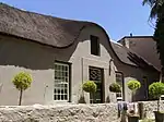 Thatched roofed building with white plastered walls.
Front and back facades with dormer gables and good Georgian doors and windows are almost identical.
The parsonage probably dates from the 1840s and is similar to the rectory in Bredasdorp.
It has a very unusual plan, being square with only a narrow opening giving access to the central courtyard.
The front and back facades, with dormer gables and Georg
Type of site: Parsonage
Current use: Parsonage.
The parsonage, which presumably dates from the 1840s, is an exceedingly beautiful Old Cape thatched cottage.