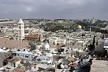 View over a city. A large building with a golden cuppola is located in the background.