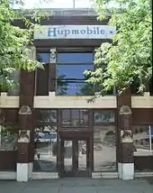 Two-story brick building with stone trim; "Hupmobile" inscribed on second floor above front door