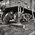 A railroad employee jacking up a gondola car to swap out a truck