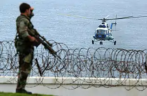 A US Military Special Operations Security Team Member observes a United Nations MI-8 Hip helicopter approaching the American embassy in Monrovia, Liberia in June 2003