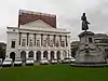 Koninklijk Theater (uitgezonderd meubilair, technische ruimtes, vloeren, wanden en omsluitende muren van de ruimte en de loges) en het monument Grétry (met uitzondering van bloemen en sluiting). Instelling beschermingszone beperkt door de voorgevel van het theater en het kleine park rondom het monument Grétry