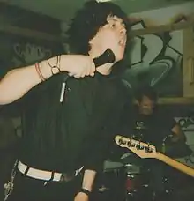 A vocalist and a drummer of a band performing with their band.