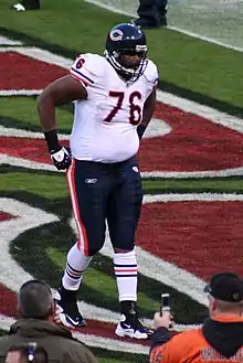 A football player wearing a white jersey with the number 76 and blue bottoms.