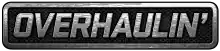 A simple logo spelling the word "Overhaulin' " in block capital letters in silver over what appears to be a car grill or interlaced gray mesh