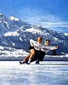 A man and woman in figure skating attire skating on ice.