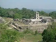 Ruins and walls of structures. A four storied square tower is in relatively good condition. The site is surrounded by forest.