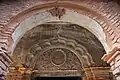 Hindu religious inscription on stucco relief under a Mughal-style arch.