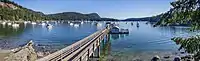 View of a bay from the shore with a wooden pier leading out into the bay.