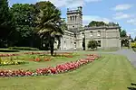 a lawn with flower beds in front of a mansion