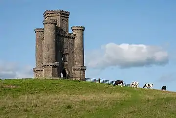 a stone tower on top of a grassy hill