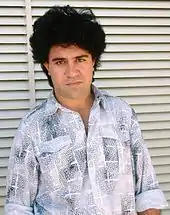 Pedro Almodóvar with black hair, wearing a bright shirt and looking to the front