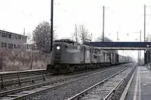 Two black electric locomotives pulling boxcars.