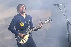 A man (Peter Morén) playing the guitar on stage.