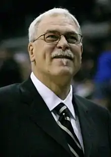 A man looking ahead. He is wearing a jacket and tie.