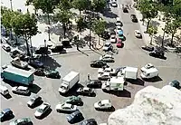 Traffic ten abreast traverses the Place de l'Étoile. This traffic circle surrounds the Arc de Triomphe at the intersection of ten two-way and two one-way streets. It has no lane markings.